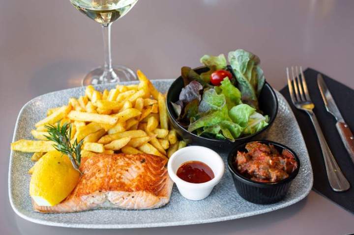 Un filet de saumon grillé, servi avec des frites et des salades Laxou