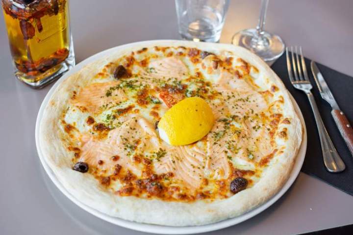 Une pizza au saumon garnie d'une moitié de citron Laxou
